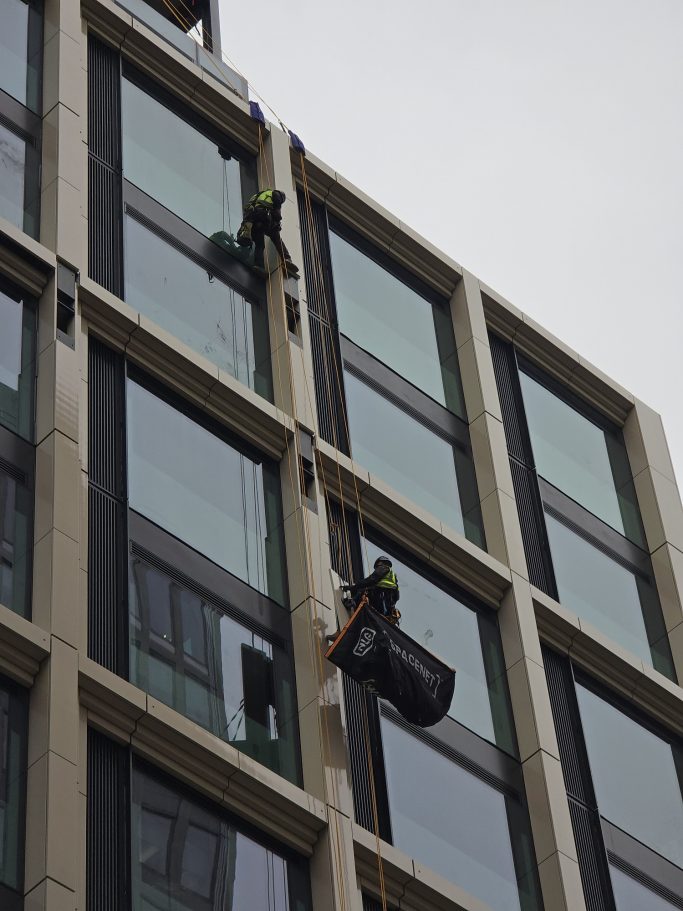 Two workers cleaning windows on a high-rise building in London